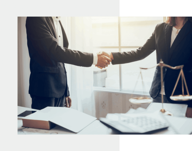 Clients love working with Aaronson law | two people shaking hands behind a desk with a scale on it.